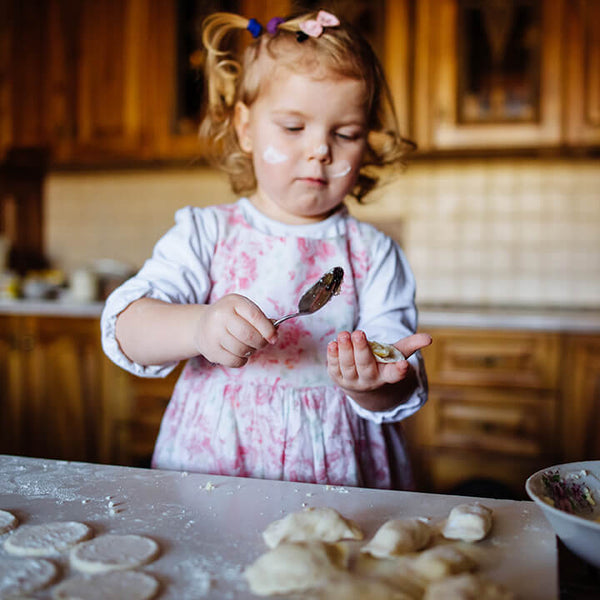 Little girl making dumplings in kitchen