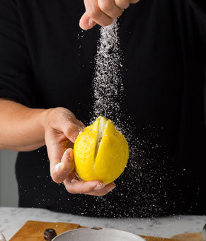 Salting a lemon with black background