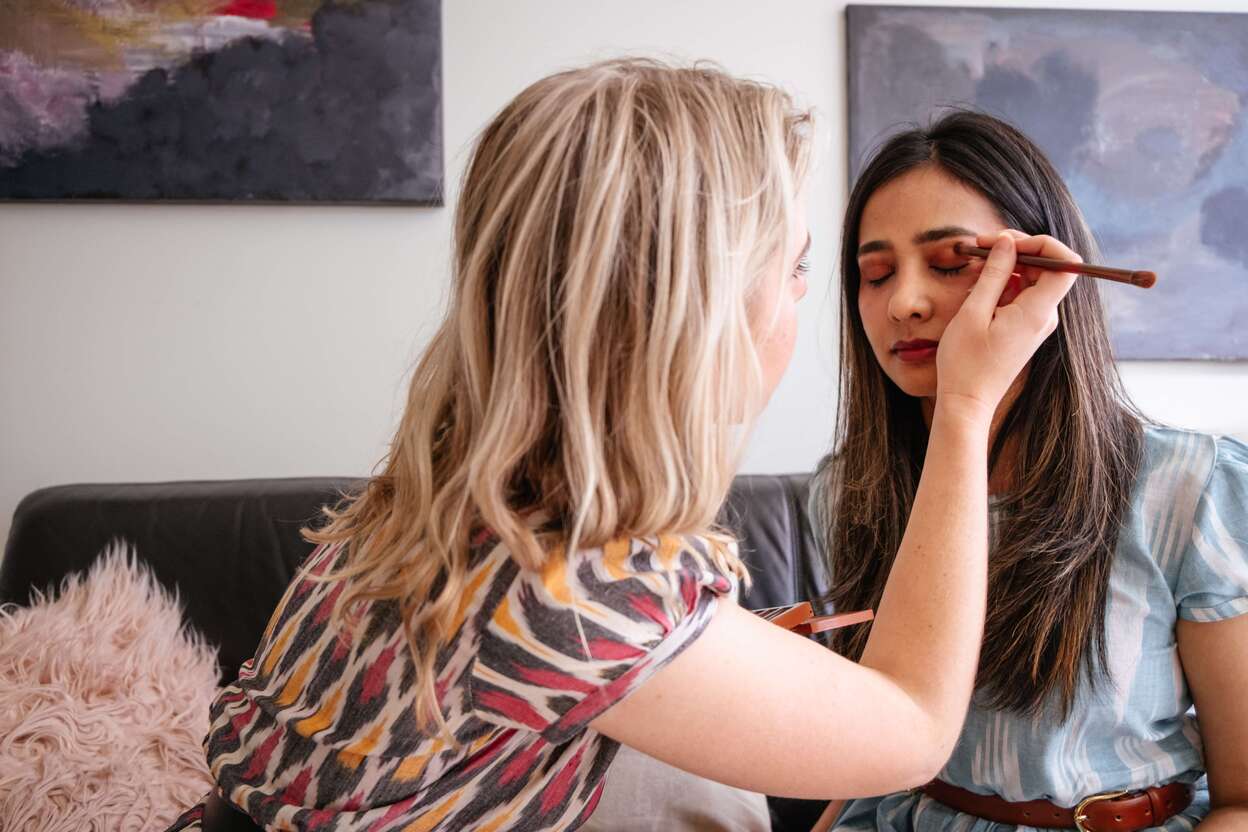 A beautician applying red eyeshadow on a woman’s eyes
