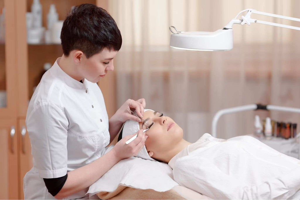 A lash technician applying eyelash extensions on a client