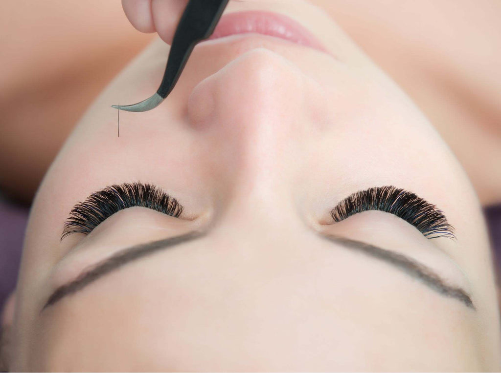 A woman with closed eyes wearing eyelash extensions