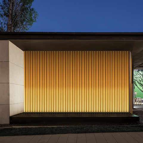 An exterior wall with vertical strips is washed by a wall washing light from bottom upward. 