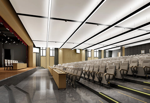 Extended LED linear lights suspended from ceiling of a small auditorium.