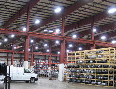 High bay LED lights suspended from ceiling of a large warehouse are illuminating the space