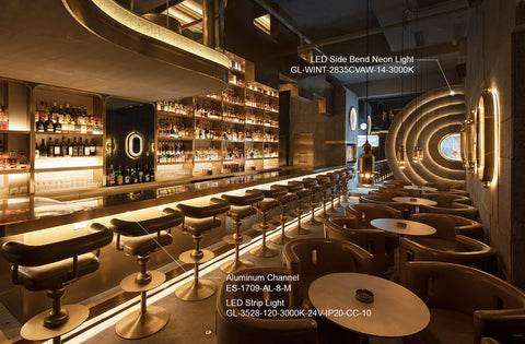 Contemporary bar with golden lighting featuring LED Side Bend Neon Light and Aluminum Channel lighting solutions, surrounded by circular booths and sleek bar stools in a sophisticated interior design.