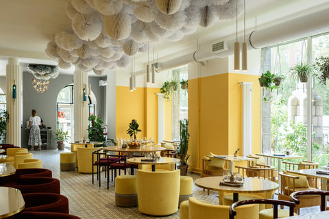 A restaurant with large windows uses natural sun light to create a warming and pleasant feeling for dinners.