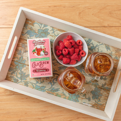a bowl of raspberries next to a box of southern breeze sweet raspberry tea