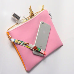 pink faux leather clutch with keys and perfume