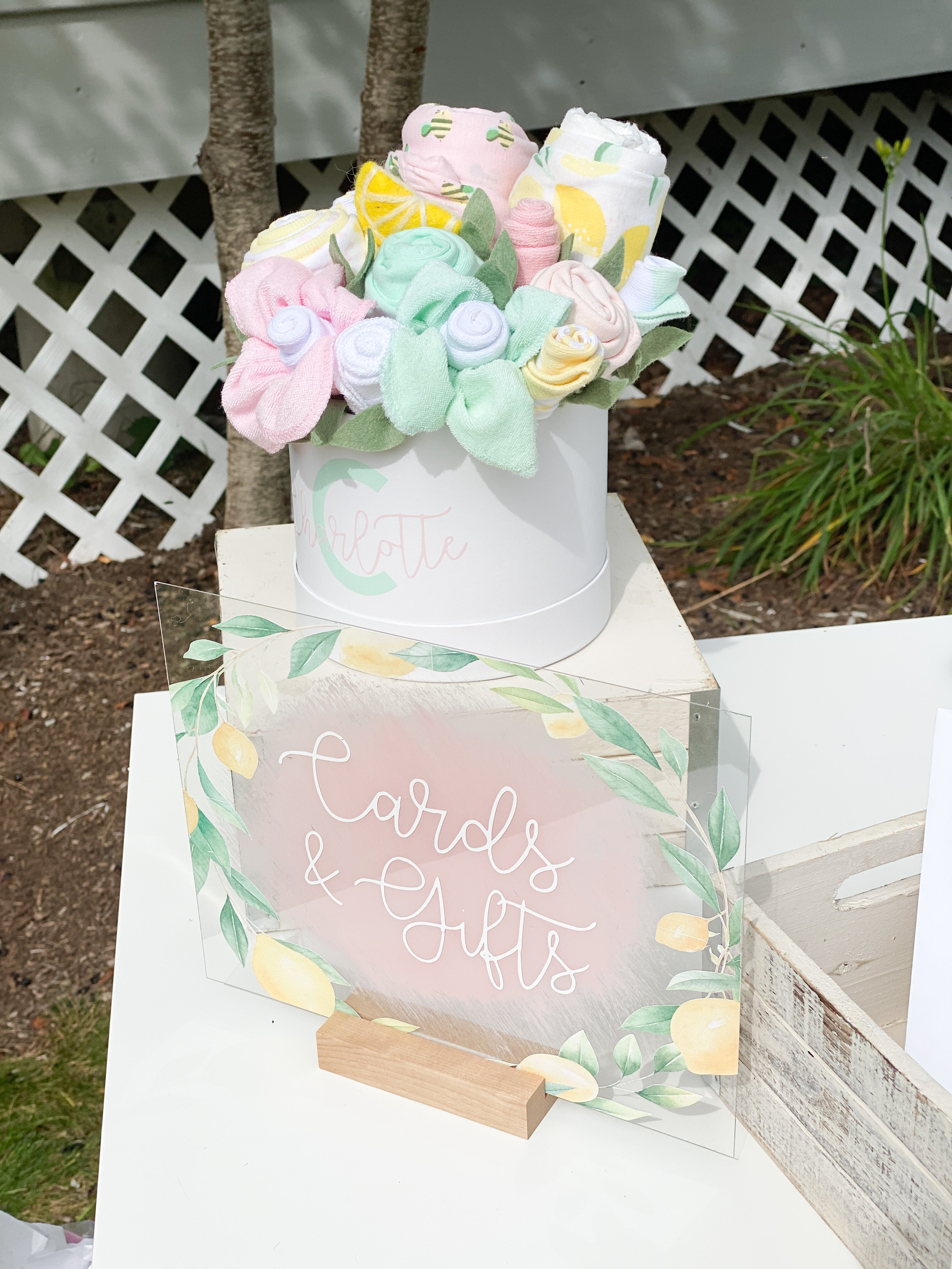lemon baby shower gift table with baby clothing bouquet and sign
