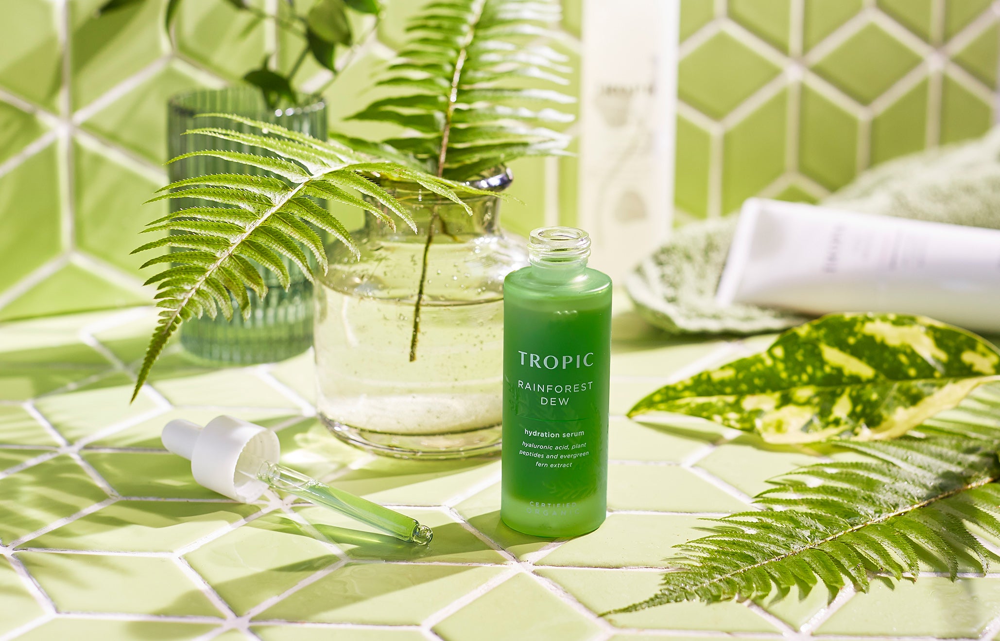 Rainforest dew hydration serum in green tiled bathroom with foliage