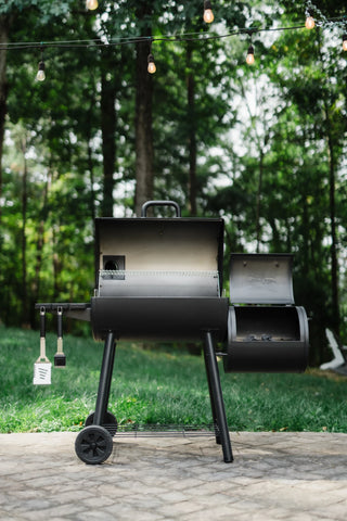 A Smokin' Pro with both lids open. The main barrel grill has a swing-away warming rack mounted in the lid. Lump charcoal is just visible in the side fire box.