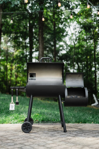 A Smokin' Pro Grill and Offset smoker sits on a paved patio with both lids open