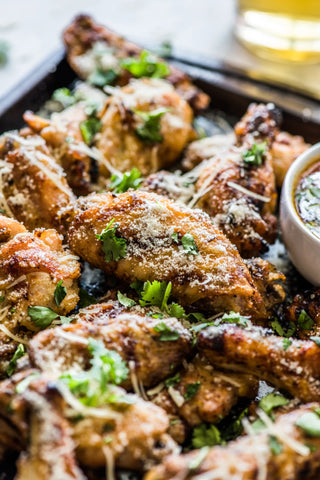 A close-up of the finished chicken wings showing the chopped cilantro and grated Parmesan cheese garnish