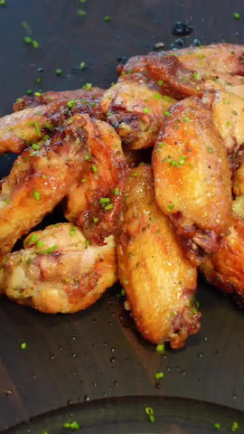 A pile of cooked, sauced, garnished, and plated wings