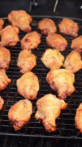 A rack of wings on a grill. The wings are just starting to turn golden brown.