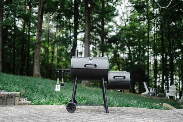 A Smokin' Pro sits outside on a paved patio in front of a green lawn and trees