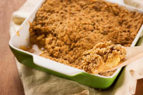 Someone uses a wooden spoon to serve apple crisp