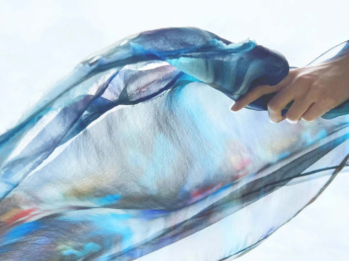 Image of hand throwing multicolour silk in wind. Click through to view the silk georgette collection and shop by fabrication.
