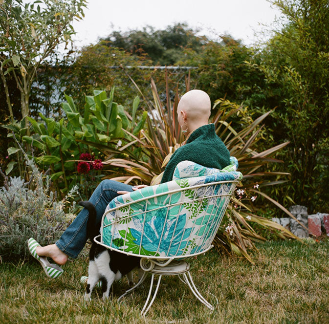 Paciente de quimioterapia con cabeza calva en el patio trasero con gato
