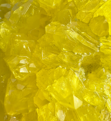 A stunning bright yellow sulfur crystal that gleams in the light. The crystal has many sharp edges, giving it a unique and intricate appearance. Its vibrant color and sparkling surface make it a captivating natural wonder. Image by Brittain Cooper Sparkle Style Co.