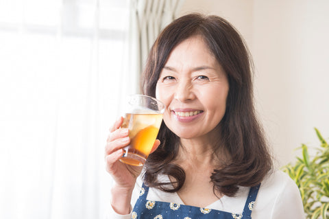 A woman drinking a kurozu beverage