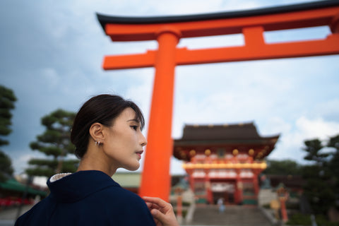 Woman dressed in a kimono walking under a torii gate