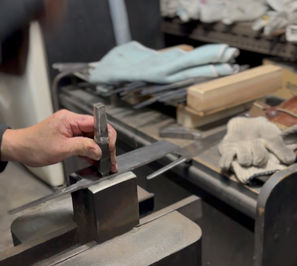 Japanese knife maker stamping a blade