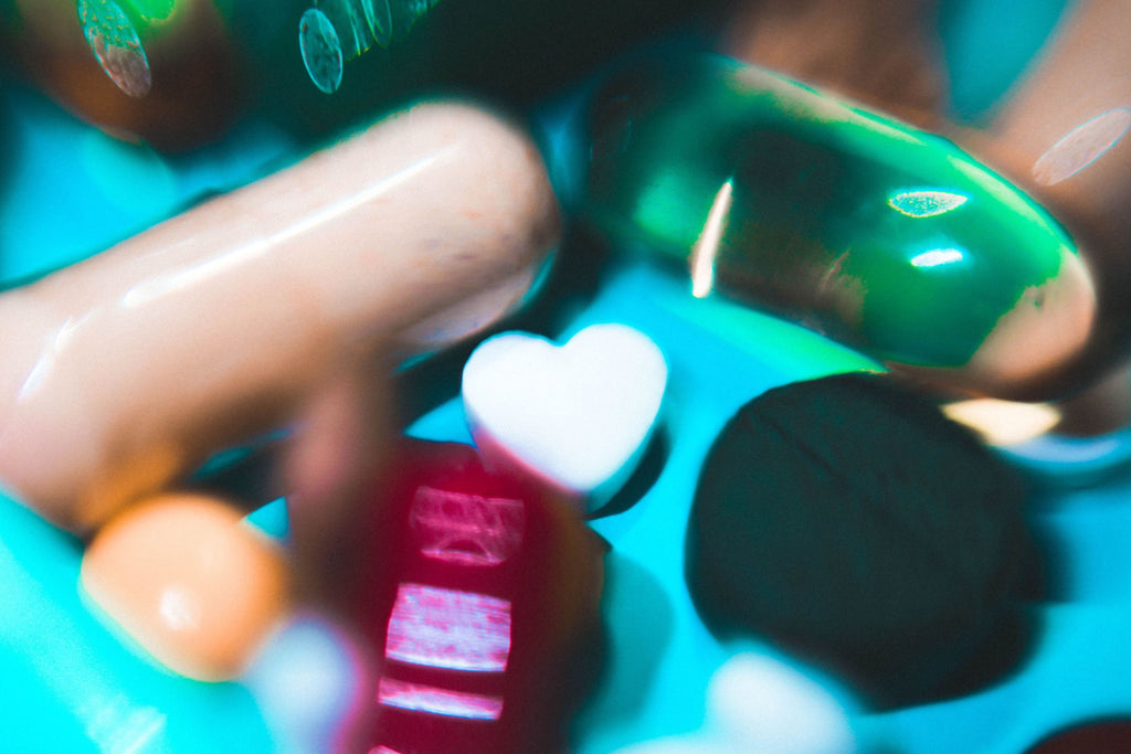 A close up of pills and pills bottles with one pill in the middle shapped as a heart