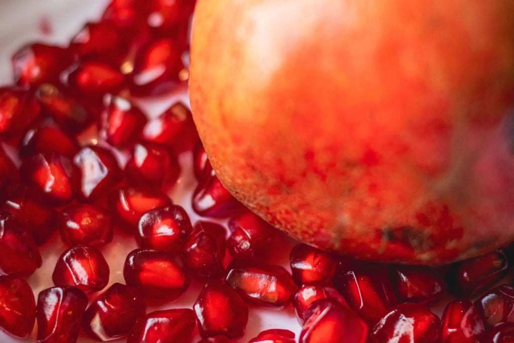 Pomegranate laying on top of pomegranate seeds