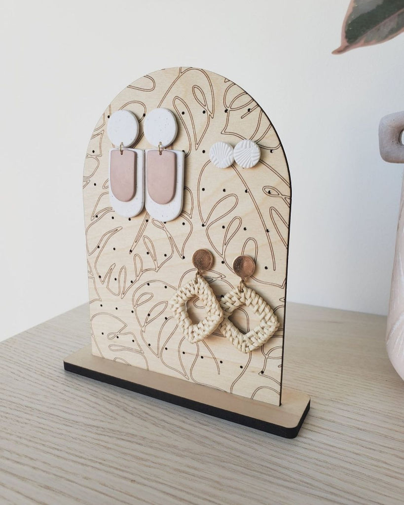 Wooden earring organizer with botanical engravings.