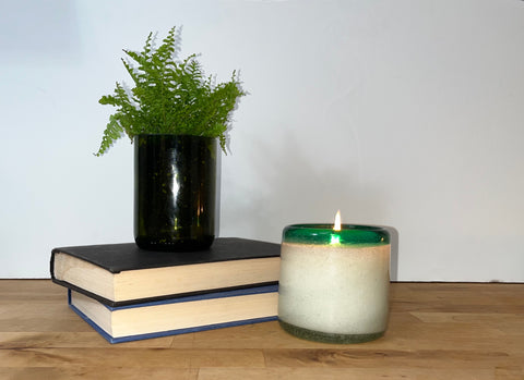 La Playa cactus flower candle next to a stack of books with a plant 