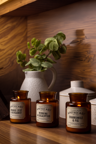 3 apothecary candles on a wooden shelf