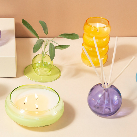 Realm glass candles and diffuser - purple diffuser with reeds, yellow tall candle, green bowl candle, and green candle holder with greenery