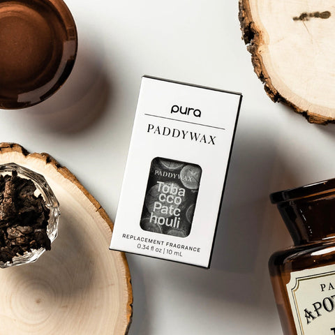 Tobacco Patchouli Paddywax Pura Diffuser Scent Pod with scent ingredients surrounding it