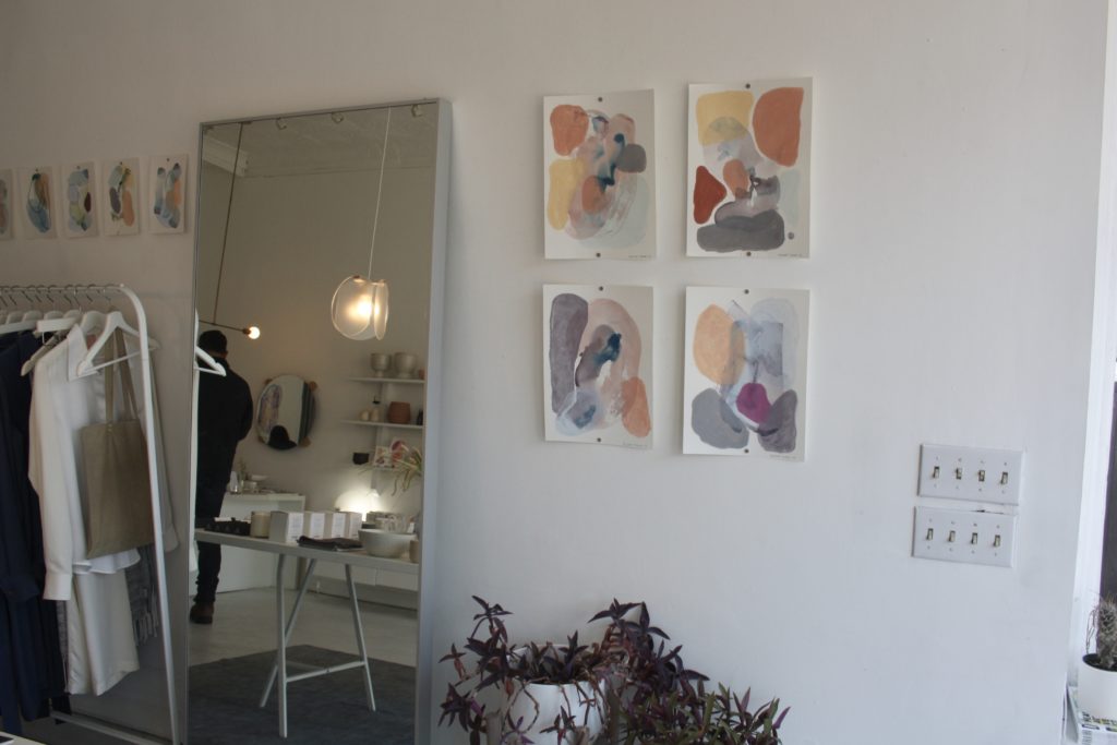 a series of paintings hung next to a mirror 