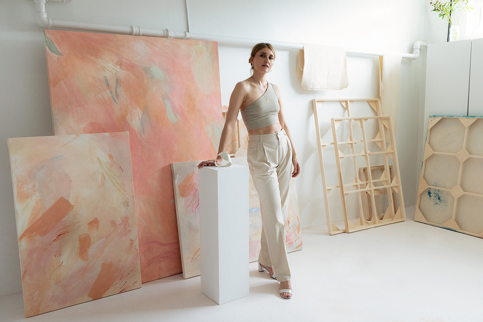 Oksana Berda the artist stands in her light filled studio surrounded by paintings