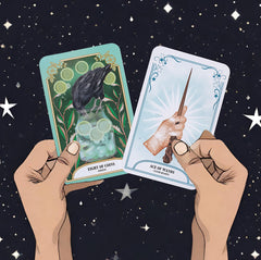 Two cards from the Crystal Magic Tarot deck (eight of coins and ace of wands) held up by hands against a background of stars in the night sky