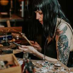 gothic jewellery designer Clare Gregory making jewelry at her workbench in Nottingham, UK.