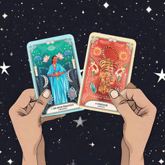 The High Priestess and Strength cards from The Crystal Magic Tarot deck held up against a starry night sky.
