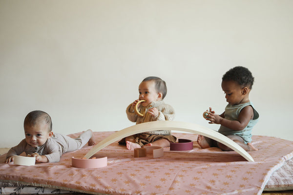 three babies playing on the floor on a toki mats play mat