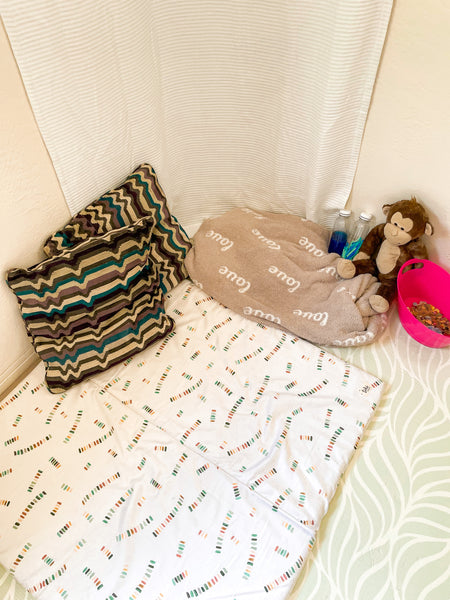 a calming corner with a toki mats play mat, pillows, and soft toys.