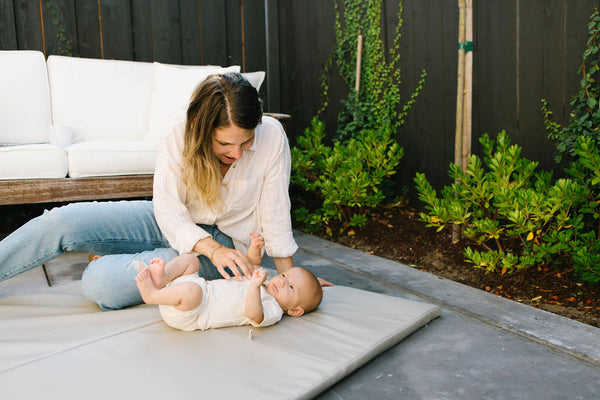 eli yonas playing with her a baby on a toki mats play mat outside