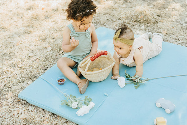 toddler and baby playing on a toki mats everywhere play mat with a vegan leather cover outside
