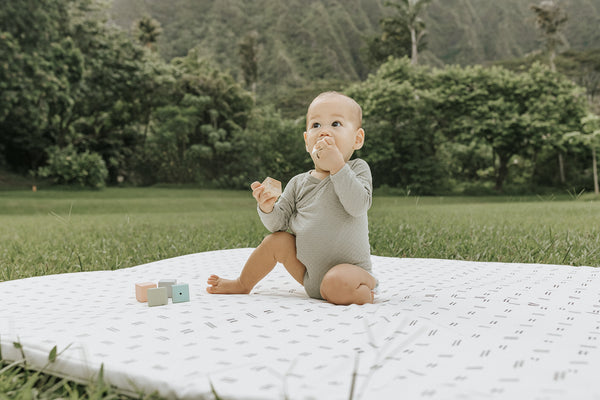 baby playing on a toki mats play mat on the grass