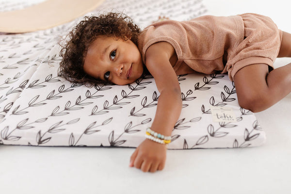 toddler laying on top of a toki mats play mat