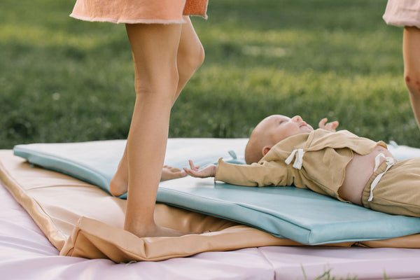 baby laying on a toki mats play mat outside on the grass