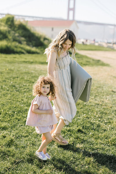 eli yonas, founder and CEO of toki mats, walking on grass with her daughter