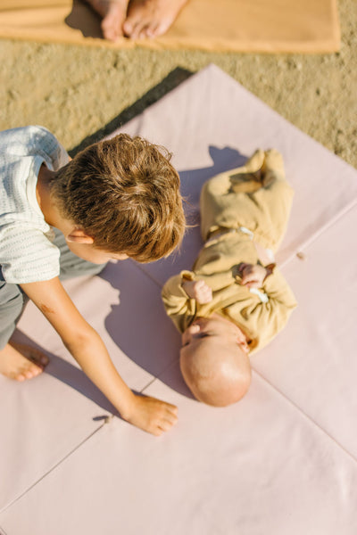 baby and older brother playing on a toki mats play mat
