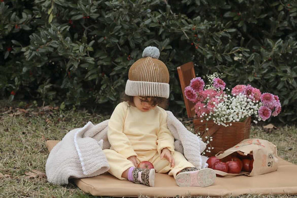 baby sitting on a toki mats padded play mat outdoors with a bouquet of flowers