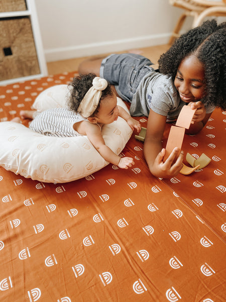 baby doing tummy time on a toki mats nursing pillow